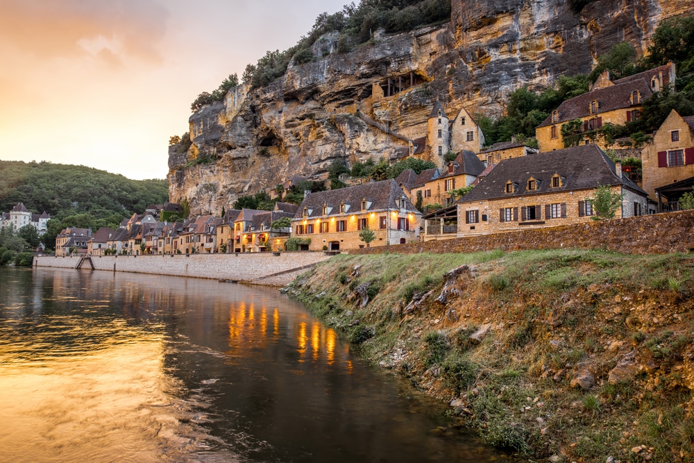 La Roque-Gageac : Village magnifique sur falaise en Dordogne Crépuscule sur La Roque-Gageac. Maisons médiévales sous la falaise de Dordogne, leurs lumières se reflétant sur l'eau.